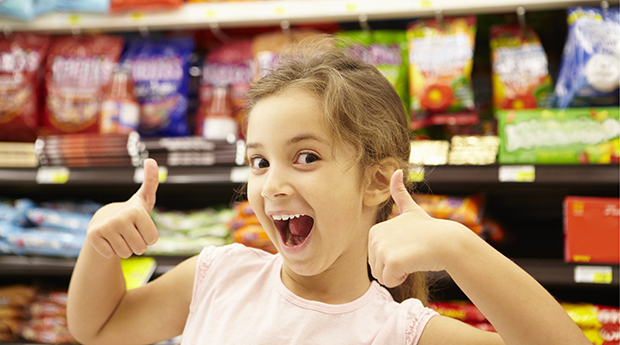 Happy young girl in grocery store snack food aisle