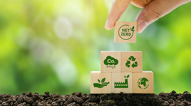 Hand stacking small wooden blocks with printed with green environmenetal icons